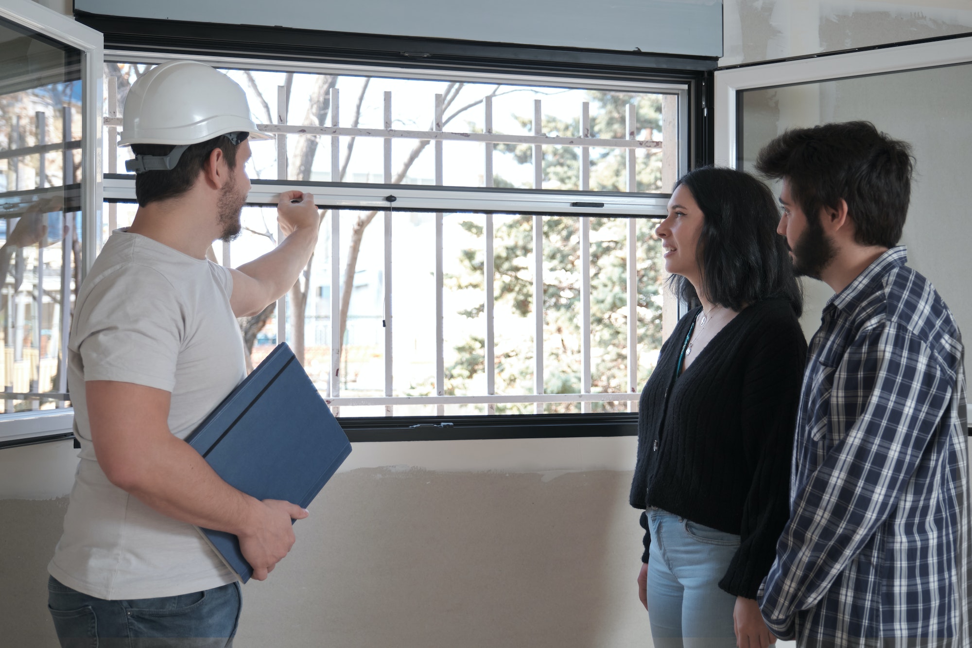 Architect shows the insect screen of the window of a new apartment to a couple.